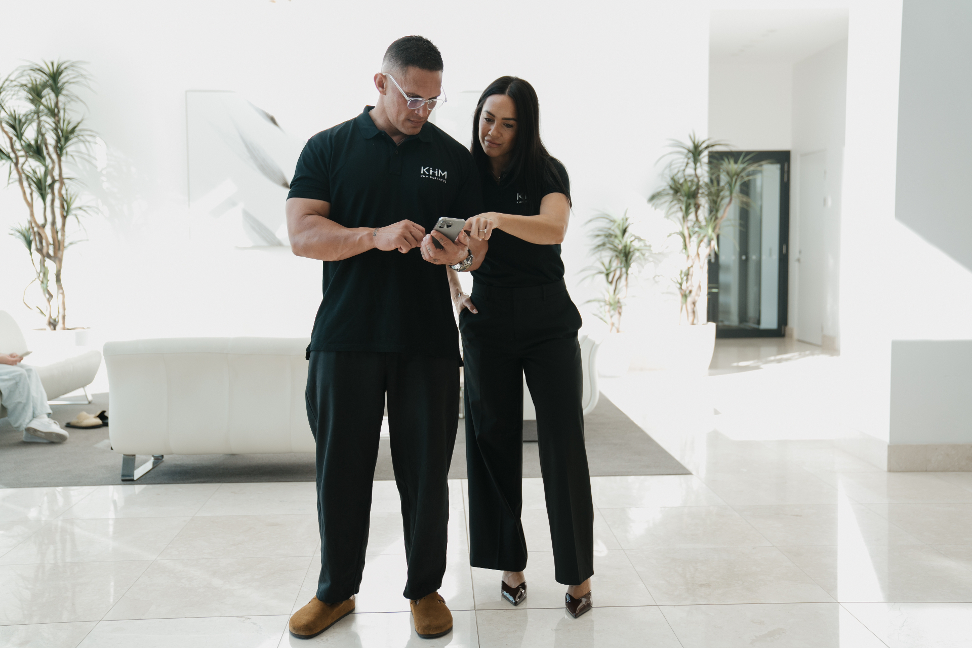 Watene and Erin from KHM Partners reviewing notes on a phone in a bright open space